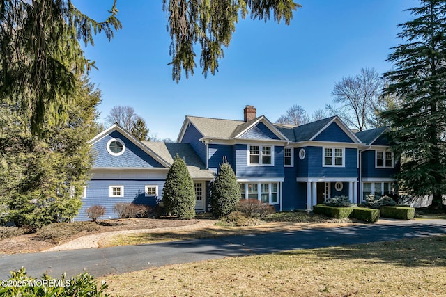 shingle-style home featuring a chimney