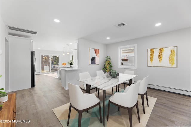 dining room featuring a baseboard heating unit and light hardwood / wood-style floors