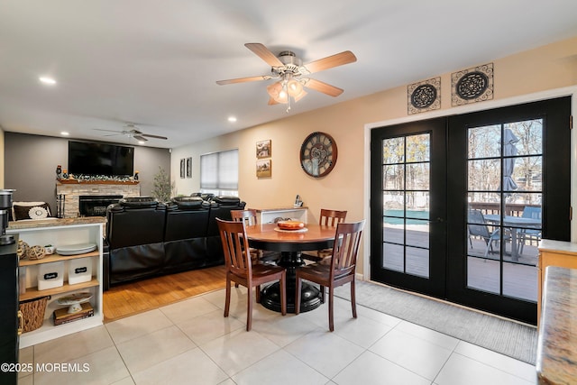 dining space featuring french doors, a stone fireplace, and light tile patterned floors