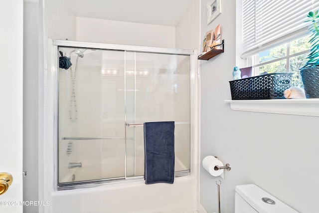 bathroom featuring toilet and combined bath / shower with glass door