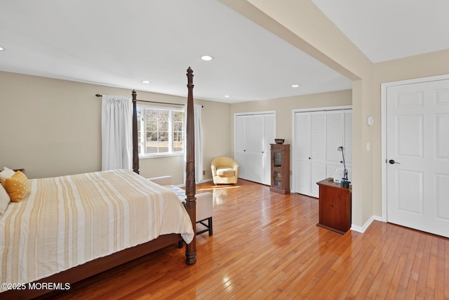 bedroom with two closets and light hardwood / wood-style flooring