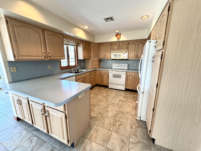 kitchen featuring white appliances, kitchen peninsula, and sink