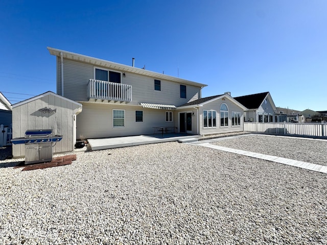 rear view of property featuring a storage shed and a patio area