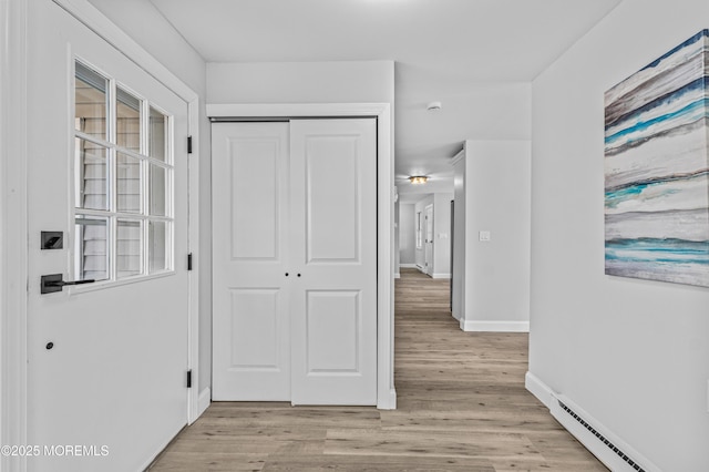 hallway with baseboard heating, light wood-style flooring, and baseboards