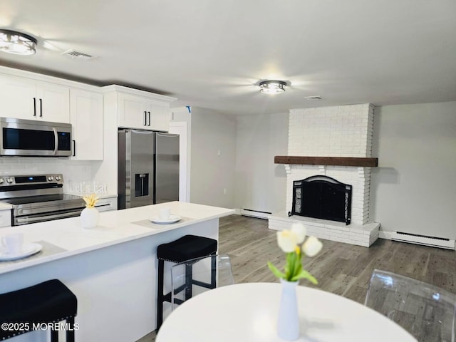 47 N Buckingham Dr, Manchester, NJ 08759 - kitchen featuring stainless steel appliances, a baseboard radiator, a breakfast bar, baseboard heating, and white cabinetry