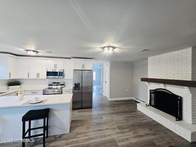 47 N Buckingham Dr, Manchester, NJ 08759 - kitchen with appliances with stainless steel finishes, light countertops, white cabinets, wood finished floors, and a brick fireplace