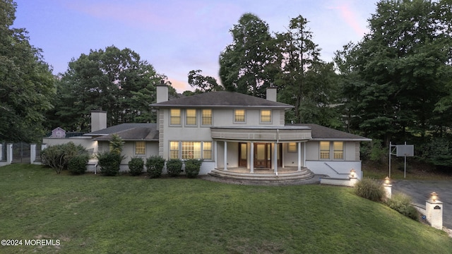 view of front of house with a yard, a chimney, and stucco siding