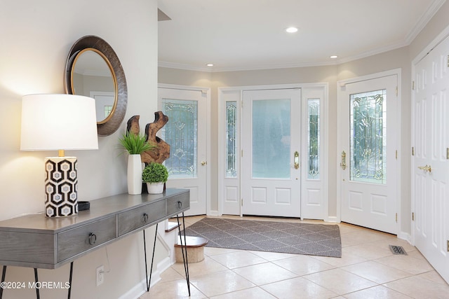 foyer entrance featuring light tile patterned floors, visible vents, and crown molding