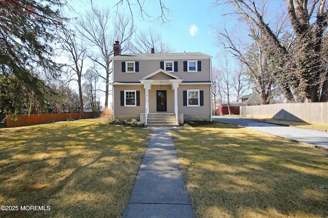 view of front of property with a chimney, fence, and a front yard