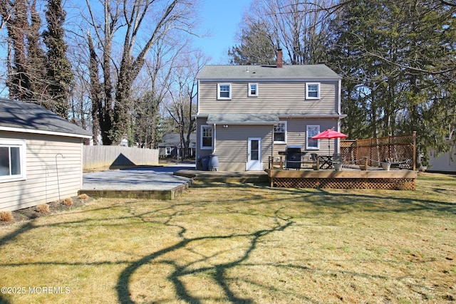 rear view of property featuring a patio, a chimney, fence, a deck, and a yard