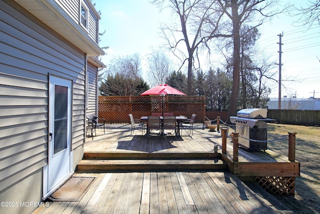 deck with outdoor dining area, fence, and a grill