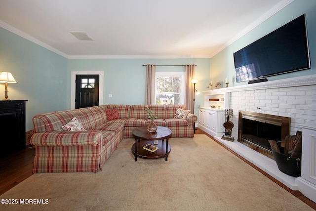 living area with visible vents, a fireplace, ornamental molding, and light wood-style flooring