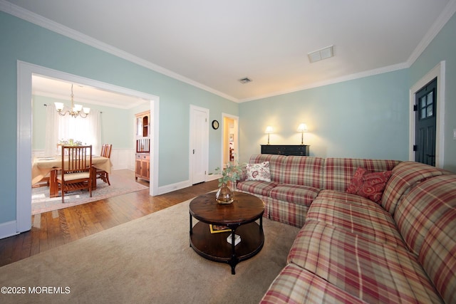 living room featuring ornamental molding, wood finished floors, visible vents, and an inviting chandelier