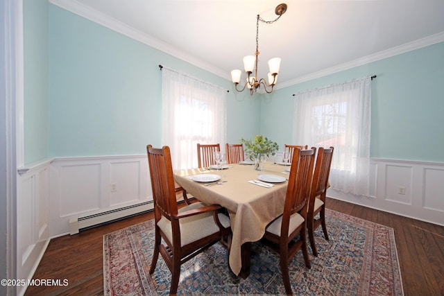 dining area with a baseboard heating unit, ornamental molding, wood finished floors, and wainscoting