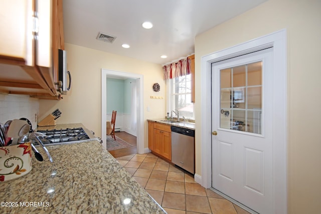 kitchen with stainless steel appliances, visible vents, backsplash, light tile patterned flooring, and a sink