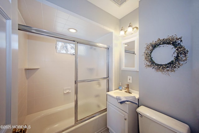 bathroom with visible vents, vanity, toilet, and bath / shower combo with glass door