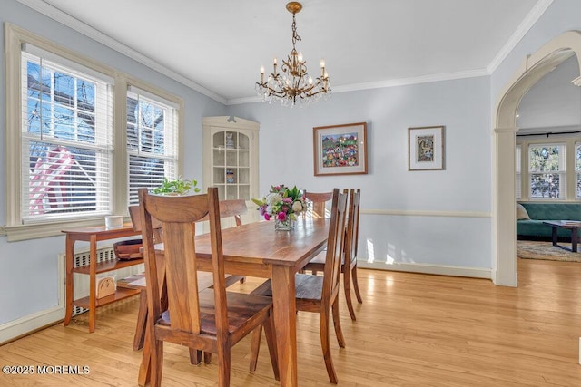 dining area with arched walkways, crown molding, a chandelier, light wood-type flooring, and baseboards