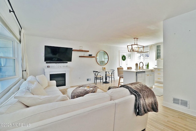 living room with sink, an inviting chandelier, and light hardwood / wood-style flooring