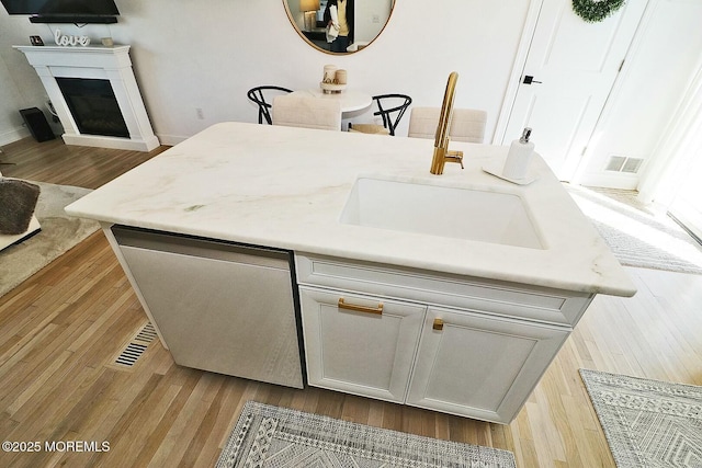 kitchen featuring white cabinetry, a center island, dishwashing machine, light hardwood / wood-style floors, and sink