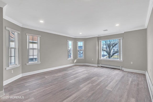 empty room featuring a wealth of natural light, light hardwood / wood-style flooring, and a baseboard heating unit