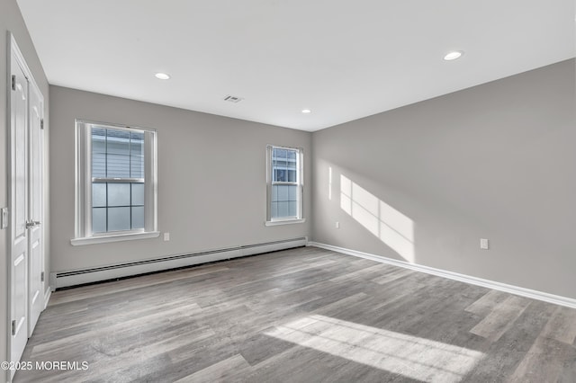 spare room with baseboard heating and light wood-type flooring