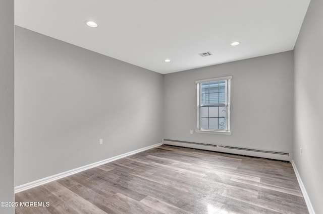 unfurnished room with a baseboard heating unit and light hardwood / wood-style flooring