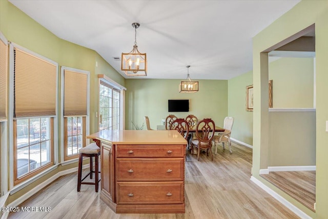 kitchen featuring a kitchen bar, a chandelier, light wood-type flooring, a kitchen island, and pendant lighting