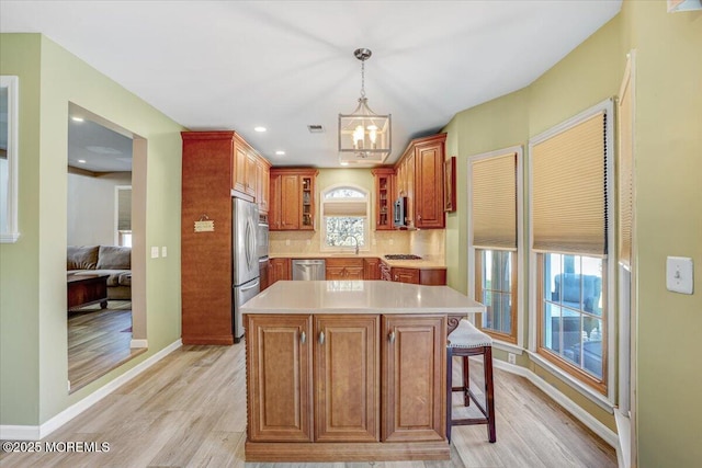 kitchen with a breakfast bar, appliances with stainless steel finishes, decorative backsplash, a kitchen island, and decorative light fixtures