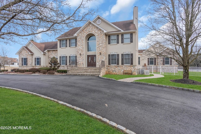 view of front of property with a front yard, a chimney, fence, and stucco siding