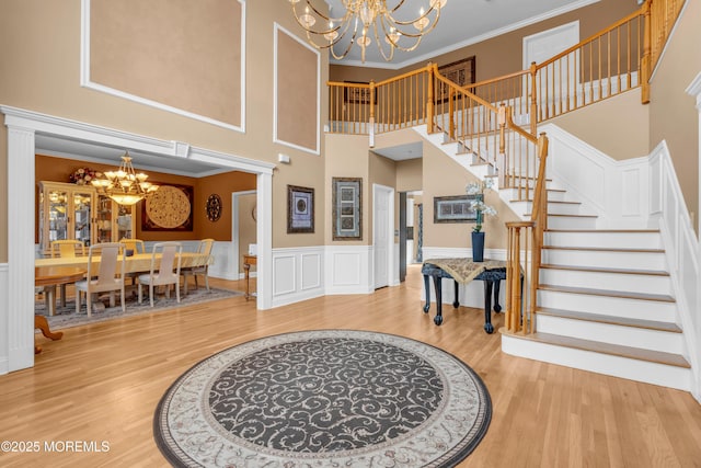 foyer entrance featuring a chandelier, ornamental molding, stairway, and wood finished floors