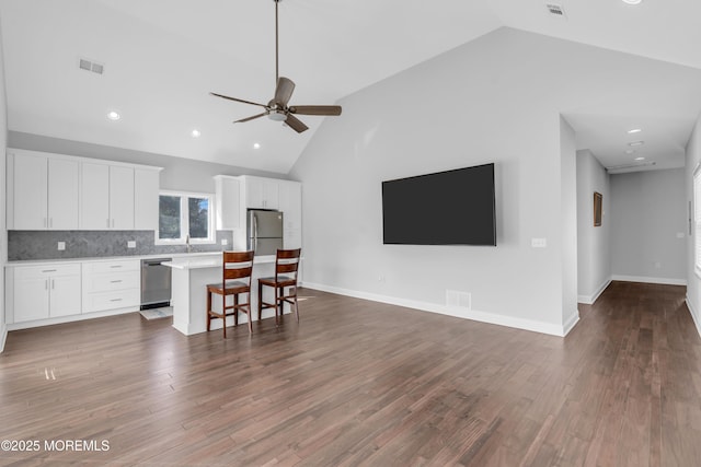 kitchen with light countertops, appliances with stainless steel finishes, open floor plan, white cabinets, and a kitchen island