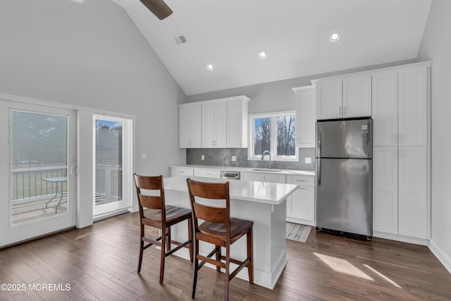 kitchen featuring white cabinets, a kitchen island, freestanding refrigerator, light countertops, and a sink