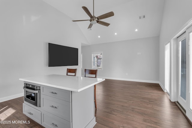 kitchen featuring dark wood-style floors, open floor plan, a center island, oven, and a kitchen bar