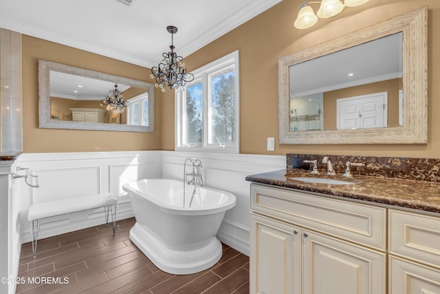 full bath featuring ornamental molding, wood finish floors, a soaking tub, and wainscoting