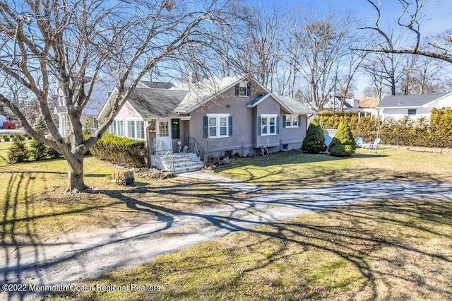 view of front of home featuring driveway, a front yard, fence, and stucco siding