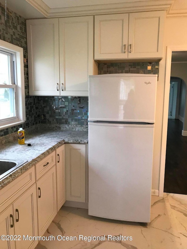 kitchen featuring white fridge, cream cabinets, and backsplash