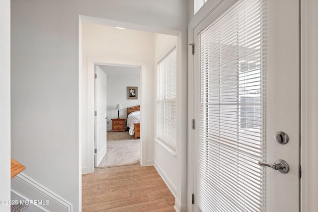 corridor with light wood-type flooring and a wealth of natural light