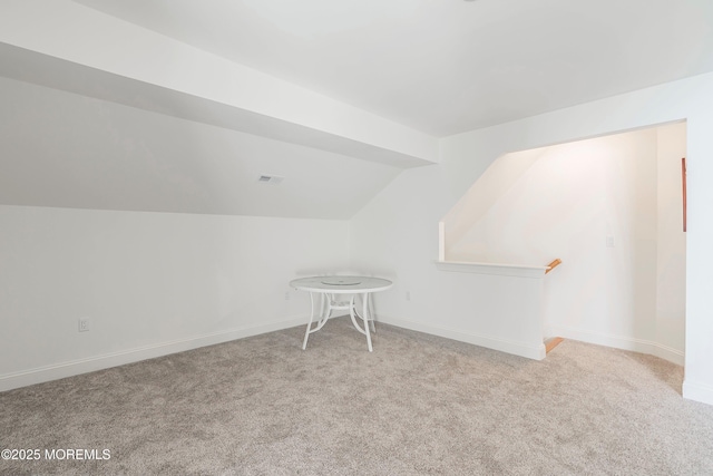 additional living space featuring vaulted ceiling and light colored carpet