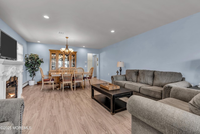 living room with visible vents, light wood-style flooring, an inviting chandelier, a fireplace, and recessed lighting