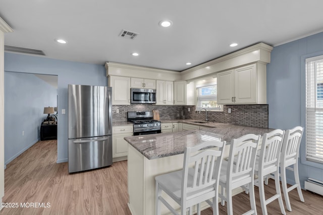 kitchen featuring a peninsula, visible vents, stainless steel appliances, and a sink