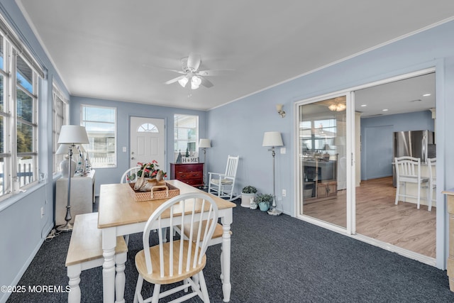 carpeted dining room with a ceiling fan and crown molding