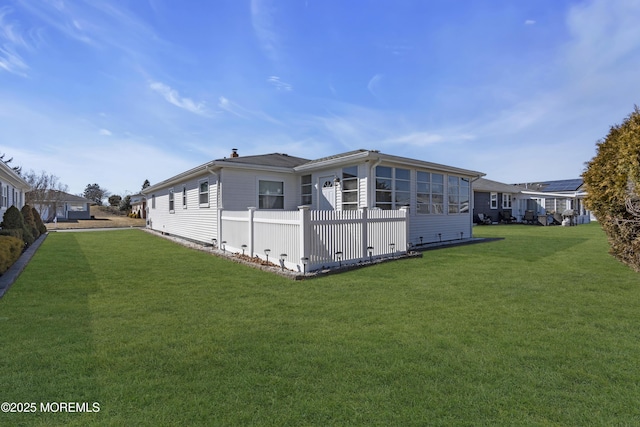 view of side of property featuring a lawn and fence