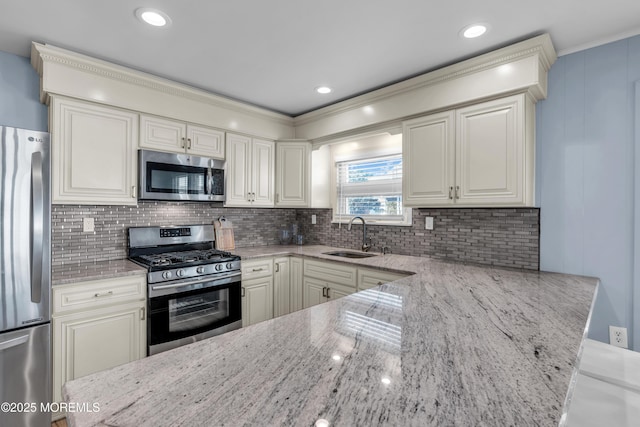 kitchen featuring light stone countertops, tasteful backsplash, stainless steel appliances, and a sink