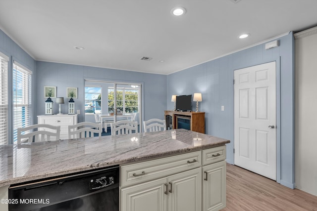 kitchen with light stone countertops, visible vents, a wealth of natural light, and dishwasher