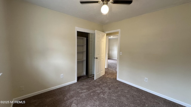 unfurnished bedroom with dark colored carpet, a closet, baseboards, and ceiling fan