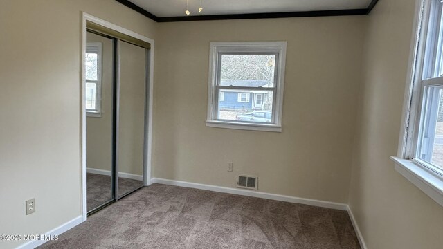 unfurnished bedroom with visible vents, multiple windows, and carpet