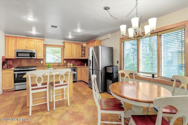 kitchen featuring a center island, a notable chandelier, sink, tasteful backsplash, and appliances with stainless steel finishes