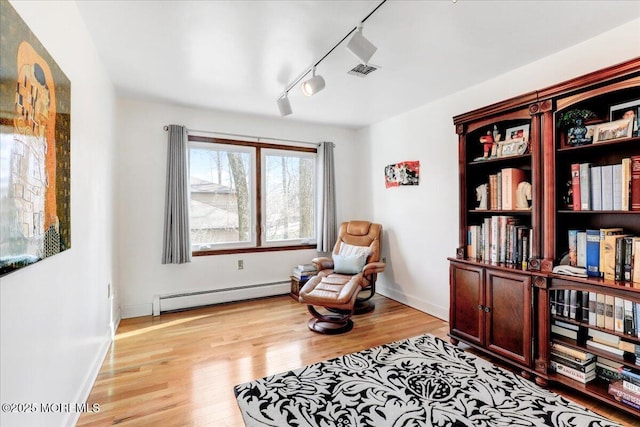 living area featuring a baseboard radiator, light hardwood / wood-style floors, and track lighting