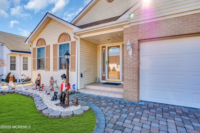 entrance to property with a garage and brick siding