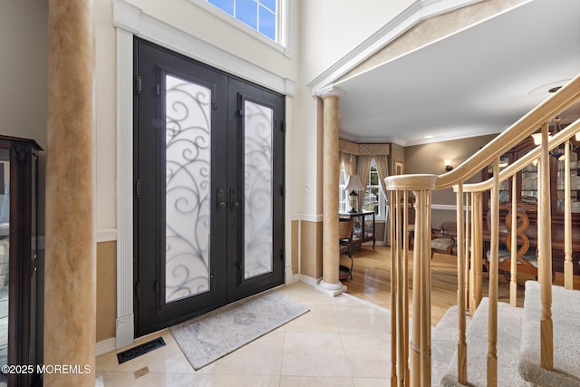 foyer entrance with french doors, crown molding, a wealth of natural light, visible vents, and ornate columns